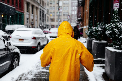 rear view of person in yellow slicker on snowy sidewalk