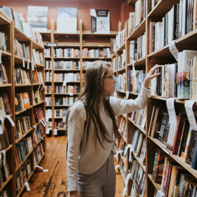 A woman browsing the fiction section of a bookstore